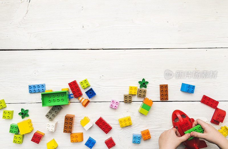 俯视图上的孩子的手玩多色塑料砖在桌子上。