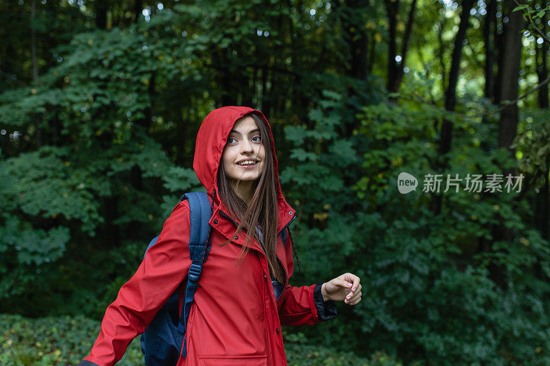 穿着红色雨衣的年轻女子在大自然中徒步旅行