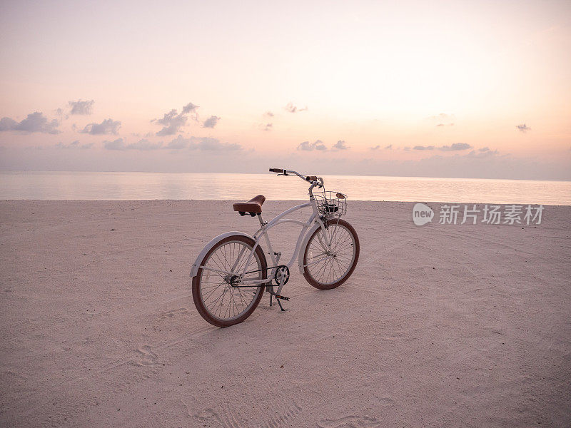 日落时在海滩上骑自行车