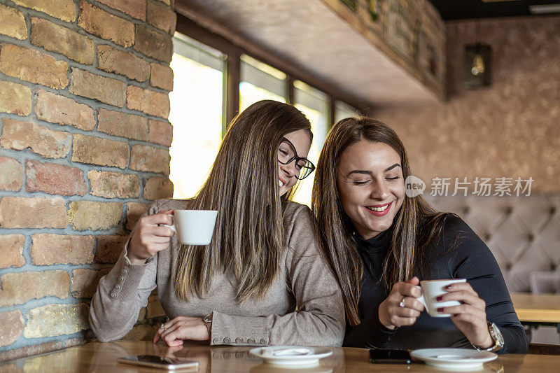 两个开心的女人在咖啡馆里喝咖啡。