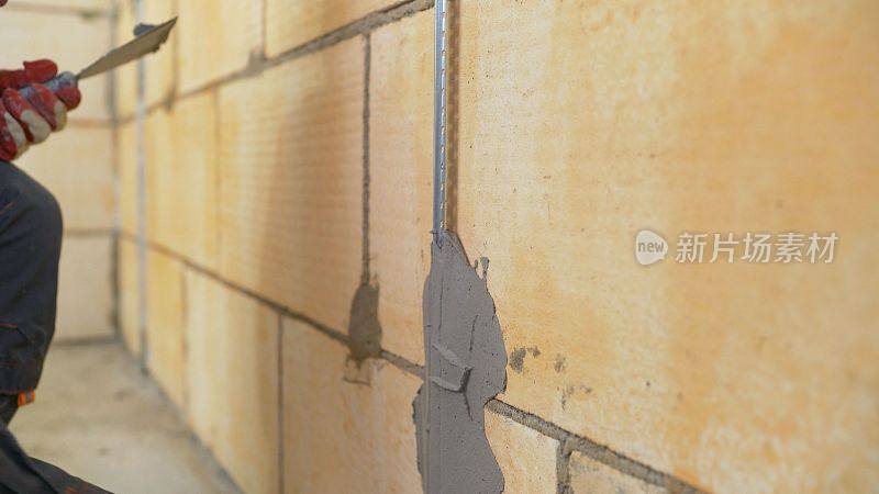 用灰泥修补墙面。泥水匠在起作用。用灰泥把建筑信标固定在墙上。