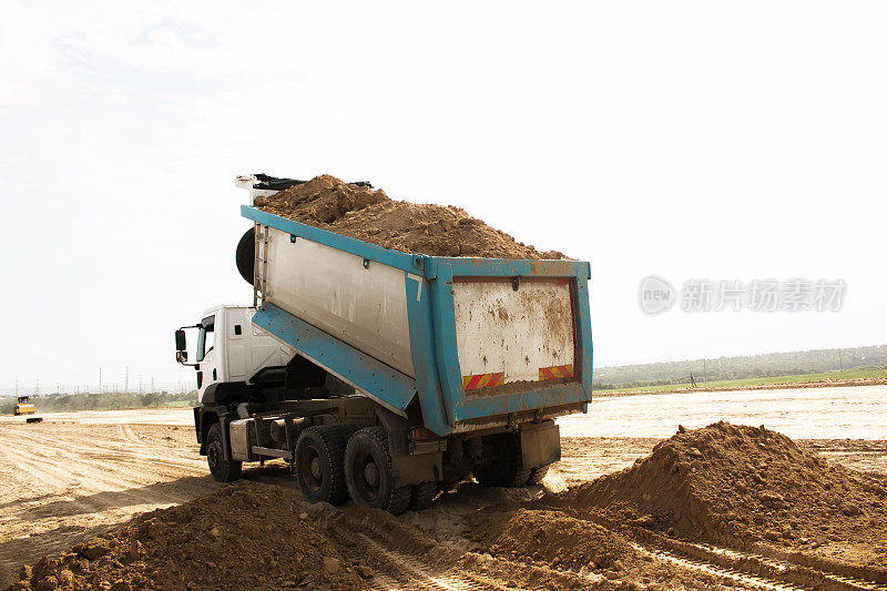 自卸车为修筑一条新公路卸载粘土。为新路打地基用的粘土。