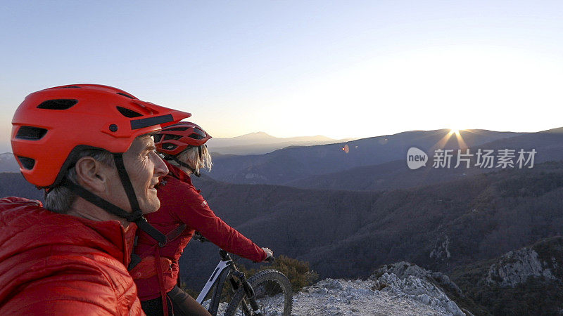 日出时分，骑山地车的情侣在山脊上放松