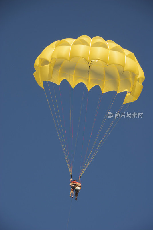一对情侣在黄色降落伞蓝色的天空一起坠落