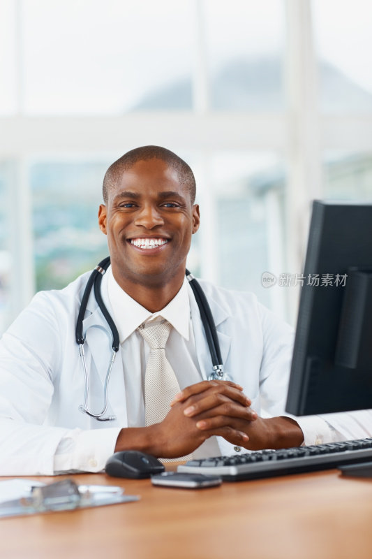 愉快的非裔美国医生坐在电脑前