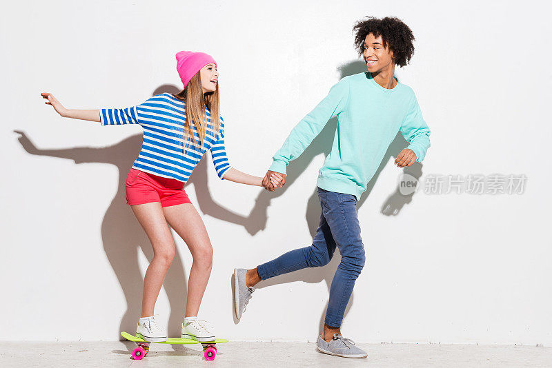 年轻夫妇和女孩手牵着手玩滑板