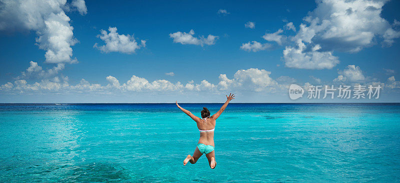 快乐的女人跳向加勒比海