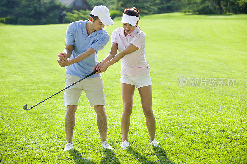 年轻男子教女朋友打高尔夫球