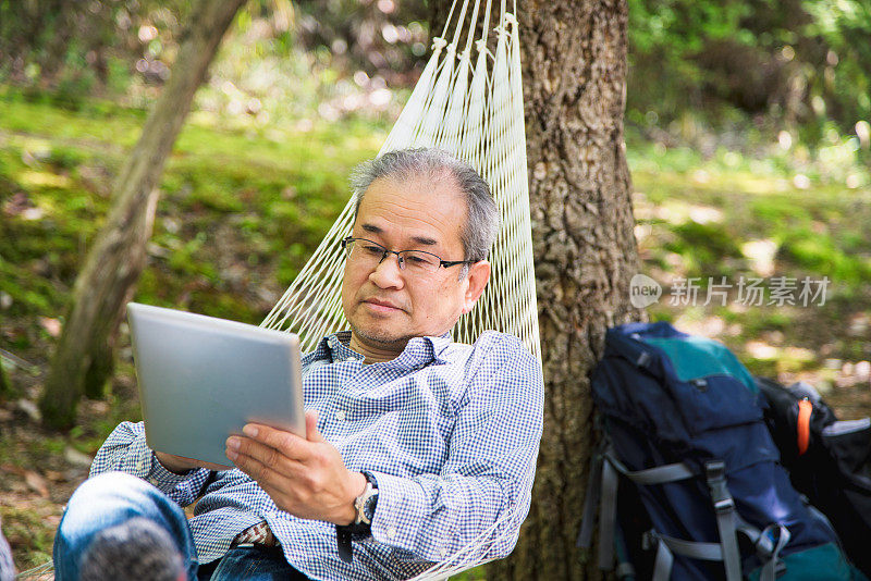 一个老人在吊床上看平板电脑