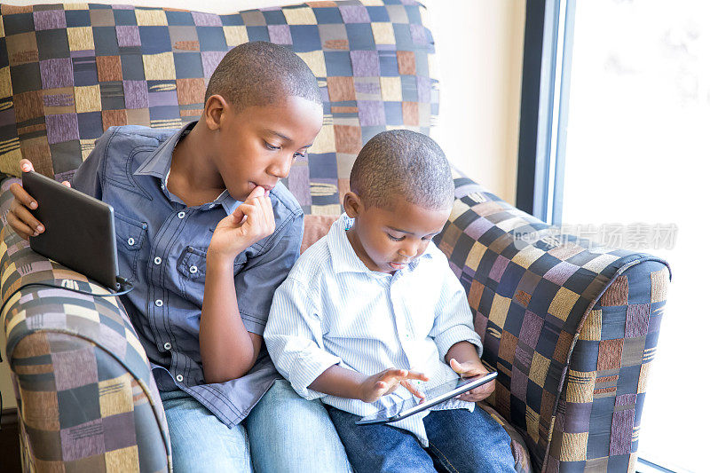 两个男孩坐在一起玩数码设备