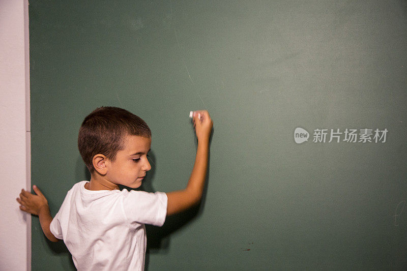 男孩站在学校黑板或黑板前。