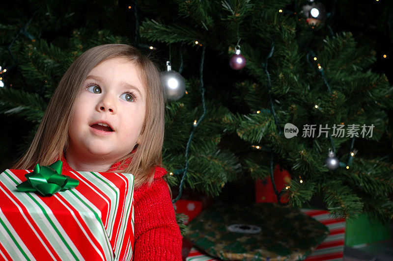 小女孩幻想着圣诞树旁的圣诞礼物
