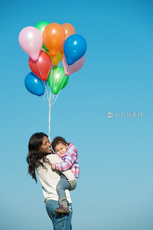 妈妈和女儿拿着一堆彩色气球。