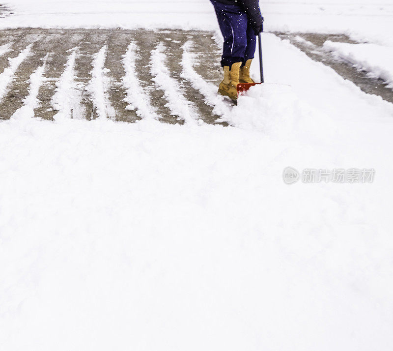 在暴风雪中从车道上铲雪的人