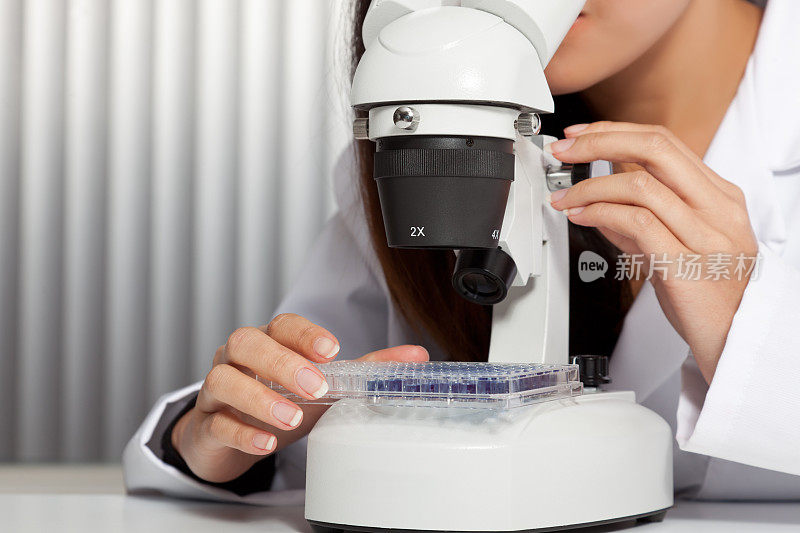 一个亚洲女人在显微镜下看