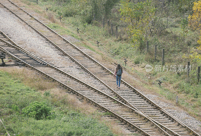背着双肩包的女孩从铁路上走远了