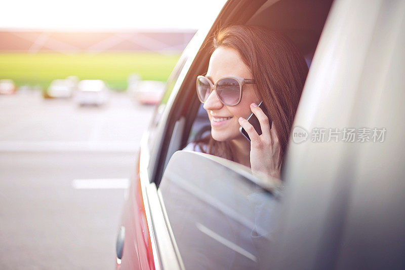 在美好的日子里，一个女人在车后座上用手机