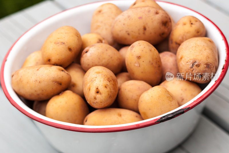 生的小土豆放在木桌上的金属碗里