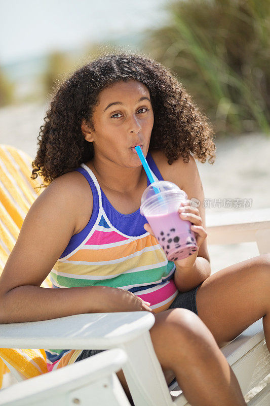 在海滩上喝草莓奶茶的女孩