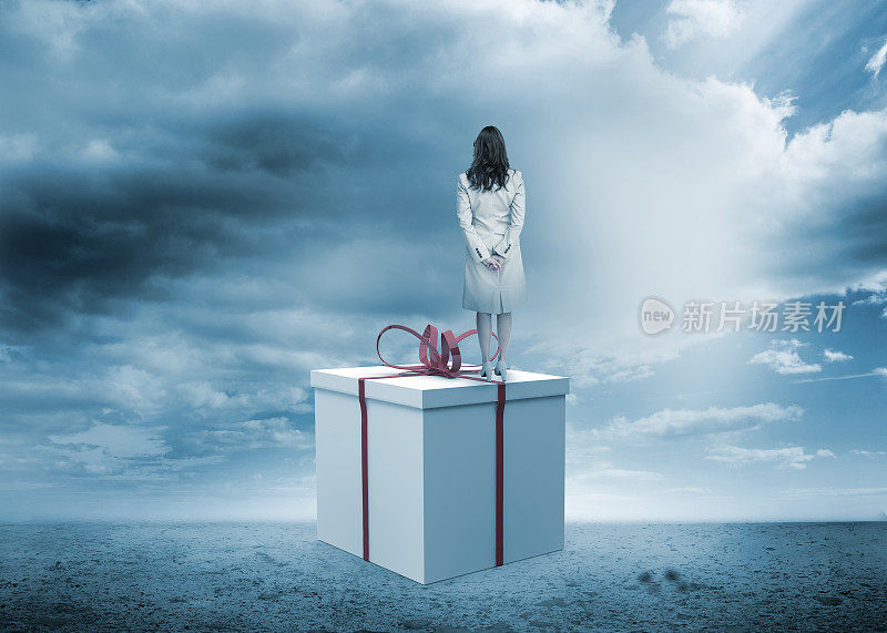 女人的背影站在一个巨大的礼品盒上
