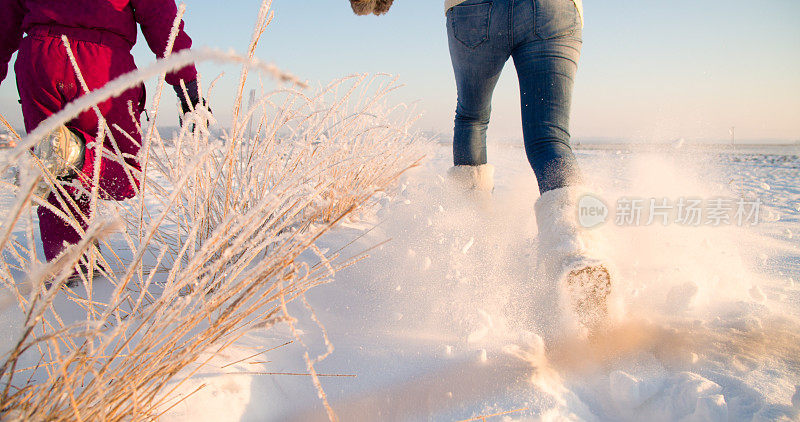 母亲和女儿在雪中奔跑