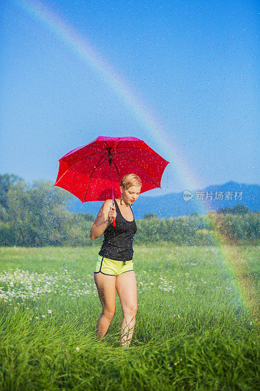 年轻的女人走在夏日的雨中