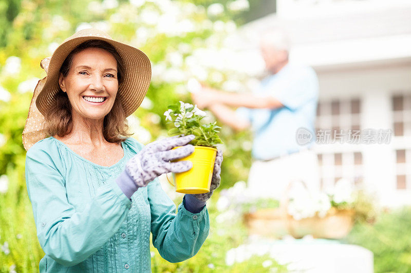 年长妇女拿着花盆，而男人在花园里园艺