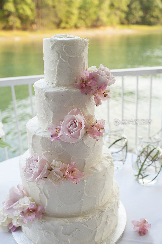 湖边有玫瑰和百合的婚礼蛋糕
