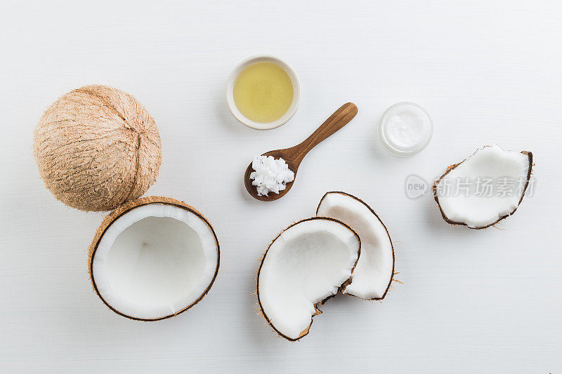 白色木桌背景上是自制的椰子制品。从俯视图看，油，磨砂，牛奶和乳液。适合空间和背景。