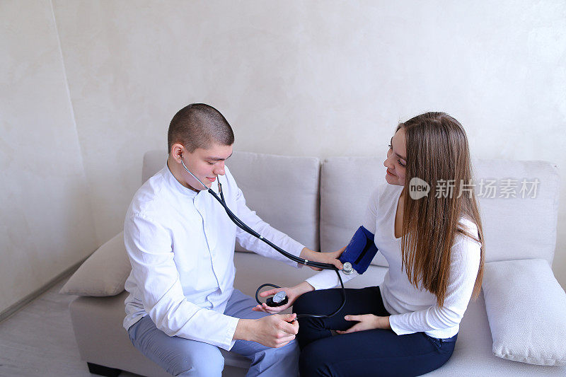 男医生用血压计测量女病人的血压