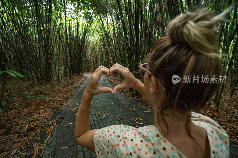 年轻女子在竹林上制作心形——印尼巴厘岛