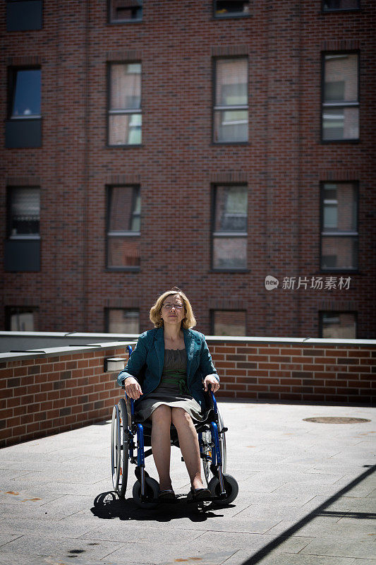 轮椅上的孤独女人被砖房包围着