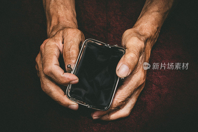 一位老人手里拿着一个空钱包。皱巴巴的手握着复古空钱包。贫困的退休概念。特殊的爽肤水