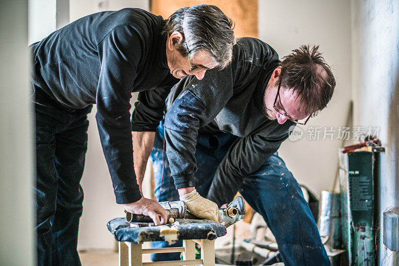 70岁的活跃老人和30岁的男人，建筑工人-水管工，一起为家庭装修工作