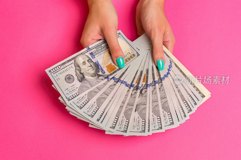 一个女人手里拿着钱。粉红色的背景。俯视图拷贝空间