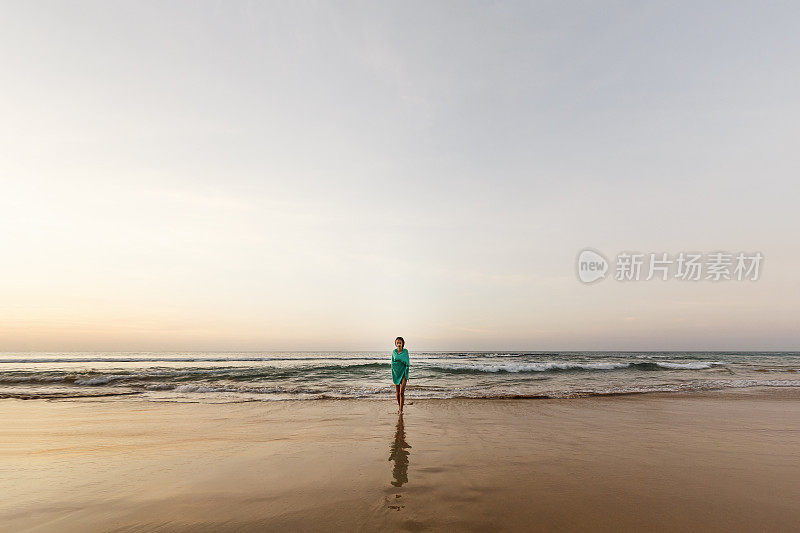 在费尔南多迪诺罗尼亚荒芜的海滩上，女孩走过潮湿的沙子