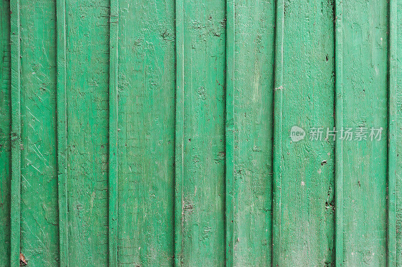 木质板的纹理呈绿色。垂直木板上的绿色油漆噼啪作响。垂直的平行线