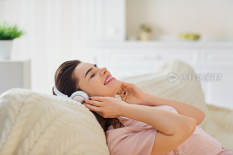 戴耳机的女孩躺在沙发上听音乐