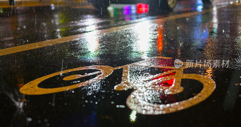 下雨天的自行车道。沥青上的自行车标志