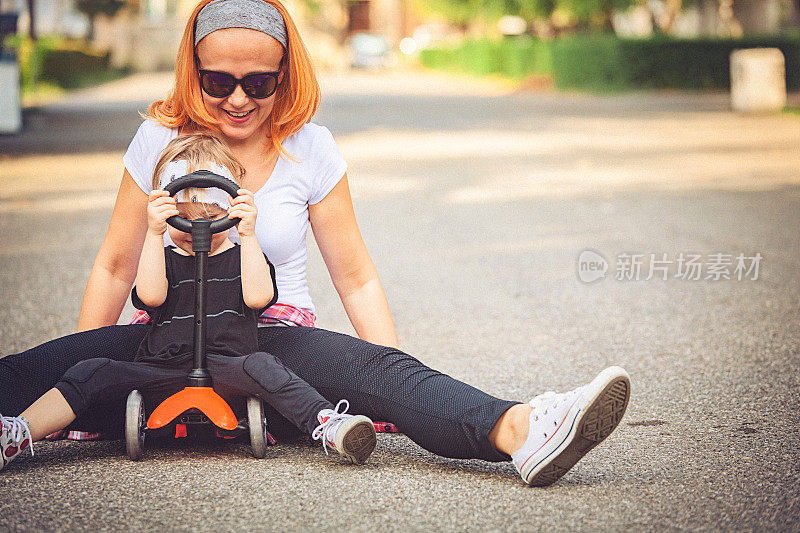 小女孩和她妈妈在公园里推着滑板车玩。