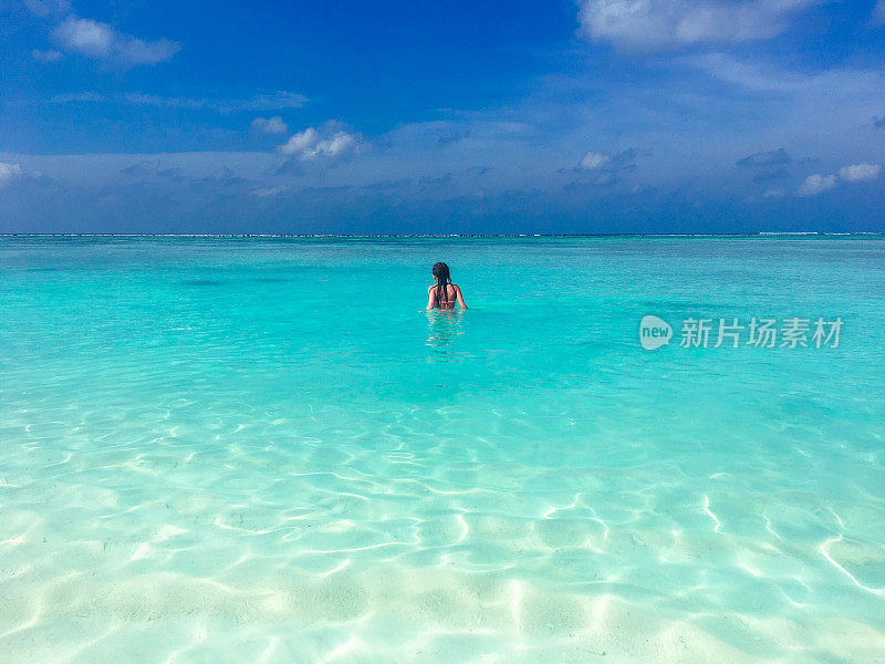 在热带岛屿上的海中漫步的女孩