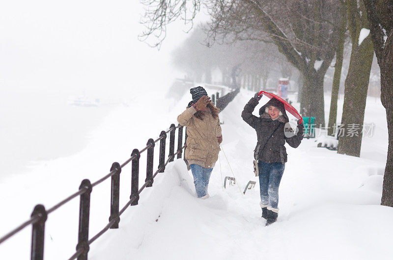 两个十几岁的女孩在暴风雪中玩雪橇