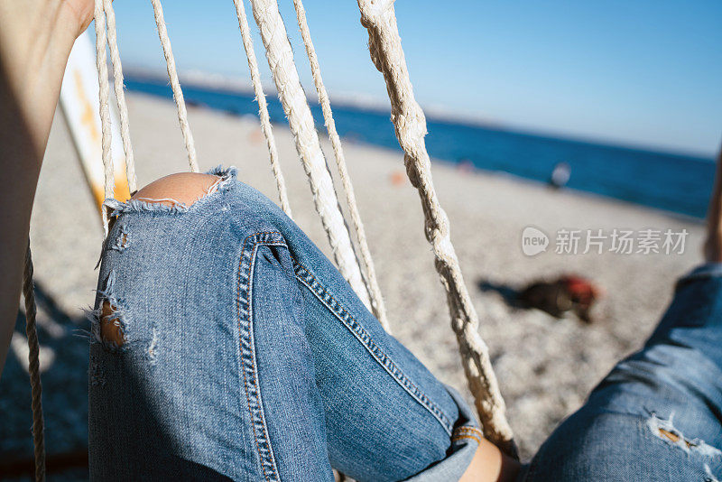 女人的腿在海滩上荡秋千