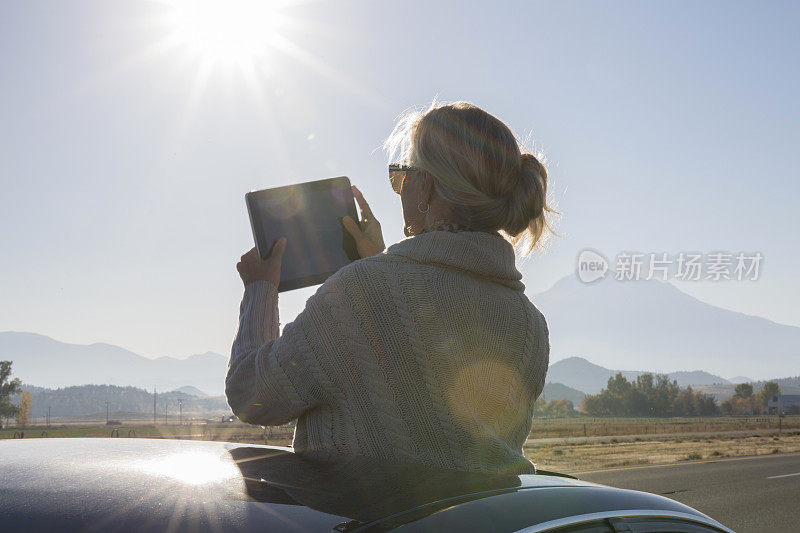 女人站在车里，在路上拍照