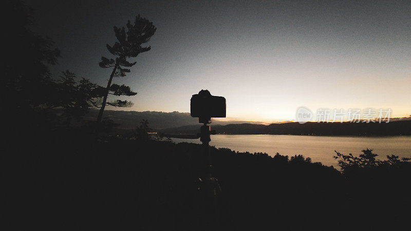 三角架上的相机在湖面上拍摄日落