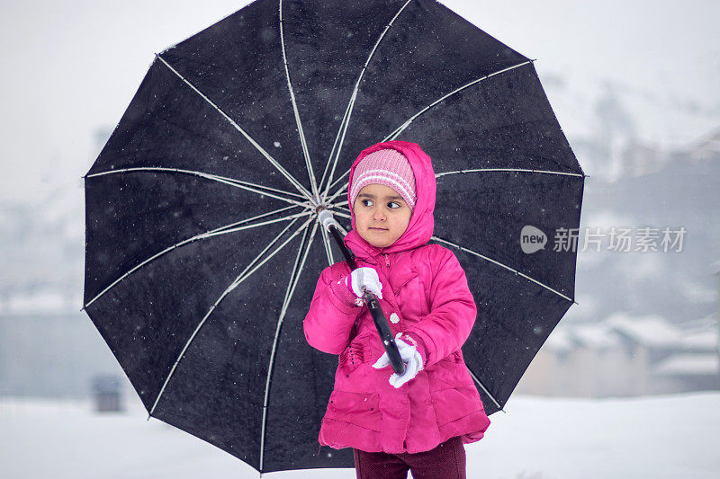 小女孩撑着伞在下雪