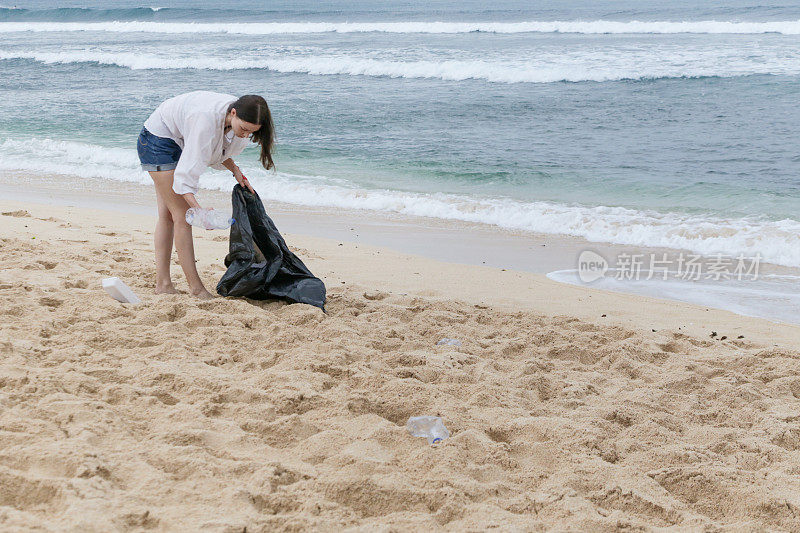 在海滩上捡垃圾的志愿者。Trash-free海域概念。一次性塑料是人类的嗜好，正在破坏我们的星球
