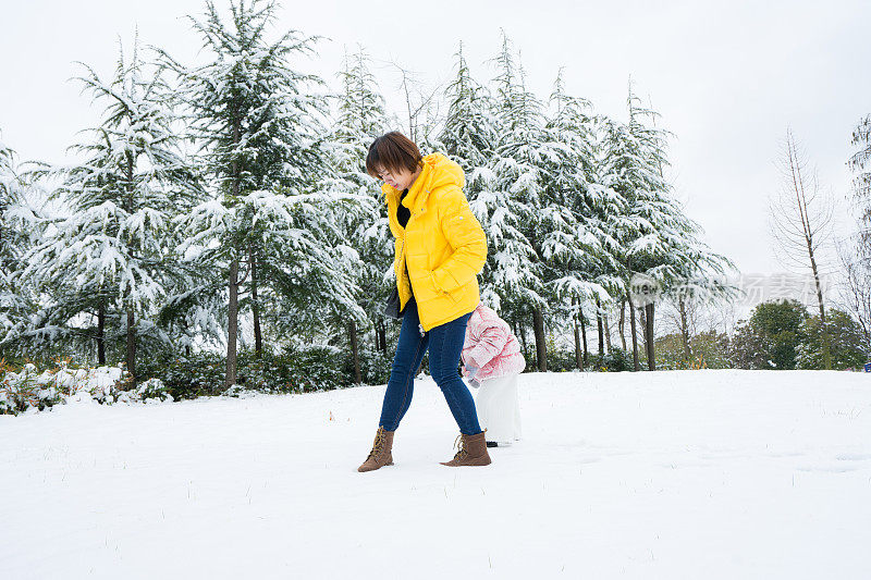 一个小女孩和妈妈在雪中玩耍