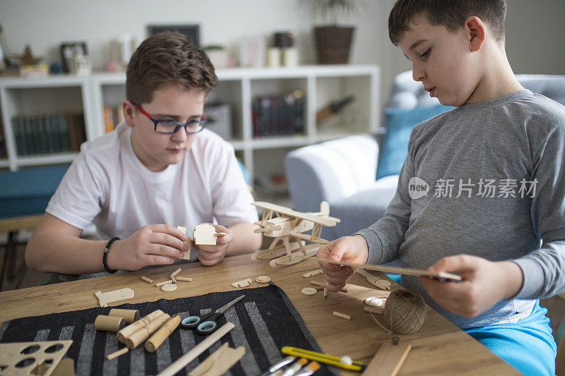 兄弟们正在为学校项目制作木制模型飞机