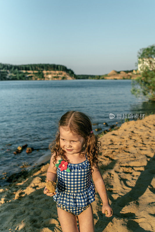 小女孩在湖边的沙滩上休息